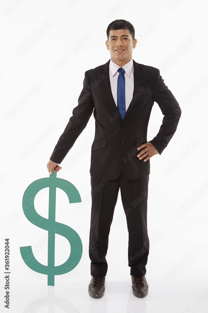 Businessman standing beside a dollar sign Businessman standing beside a dollar sign