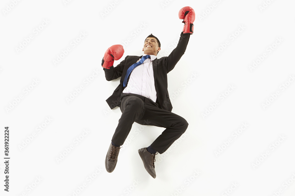 Naklejka Businessman with boxing gloves posing on the floor