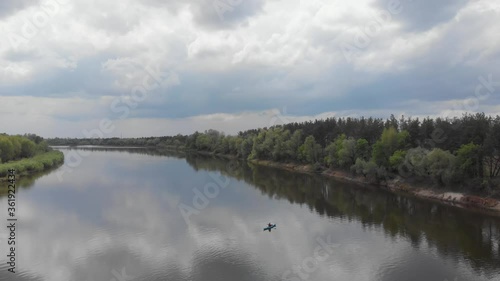 Rising up aerial of man on a blue kayak in the riverbed of a wide calm river Desna near Kyiv, travel Ukraine photo