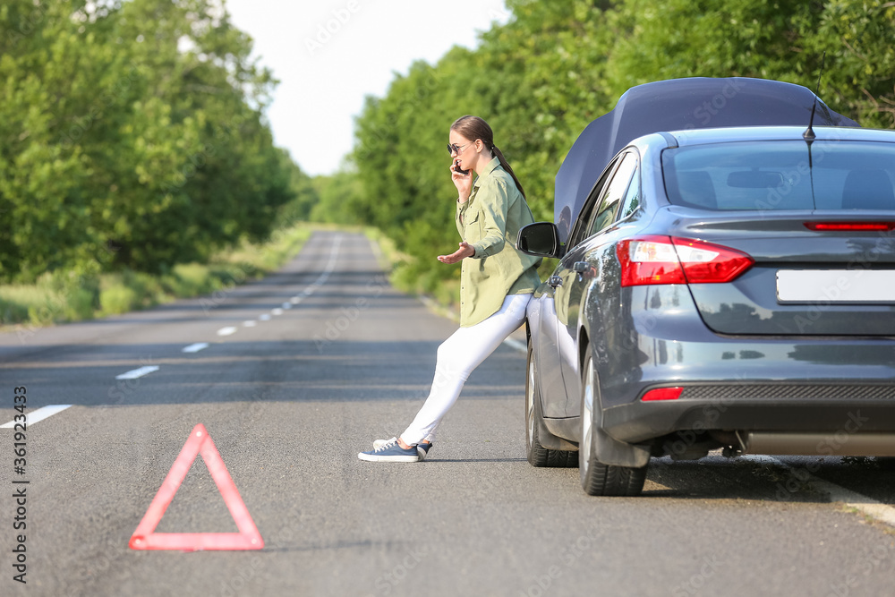 Woman calling her insurance near broken car on road Woman calling her insurance near broken car on road