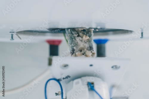 Taking out an electric heater from boiler or water heater to remove lime scale residue on it as part of a maintenance. Electric thermostat being removed from boiler.