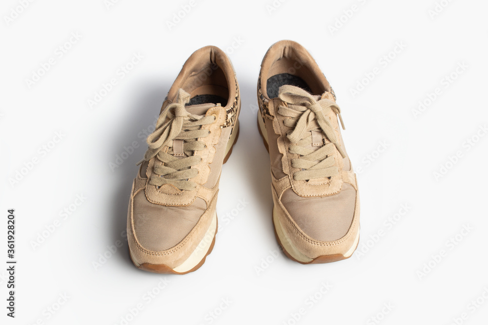 Women's beige sneakers with laces on a light background. Flat lay, top view