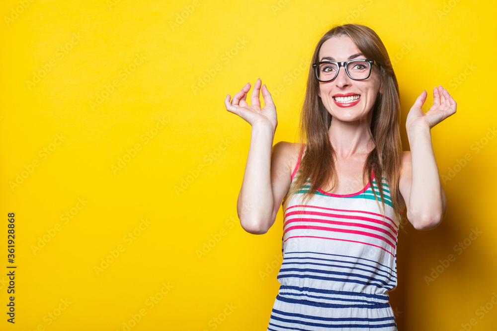 Young smiling girl dressed in a striped dress with glasses on a yellow background. Young smiling girl dressed in a striped dress with glasses on a yellow background.