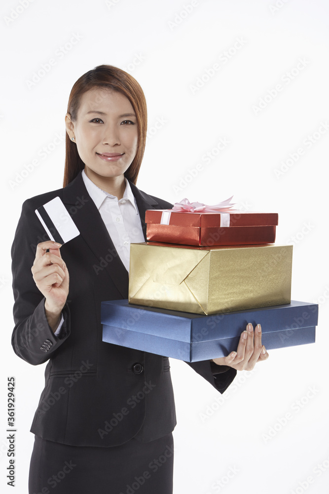 Businesswoman carrying a stack of gift boxes and holding a credit card Businesswoman carrying a stack of gift boxes and holding a credit card
