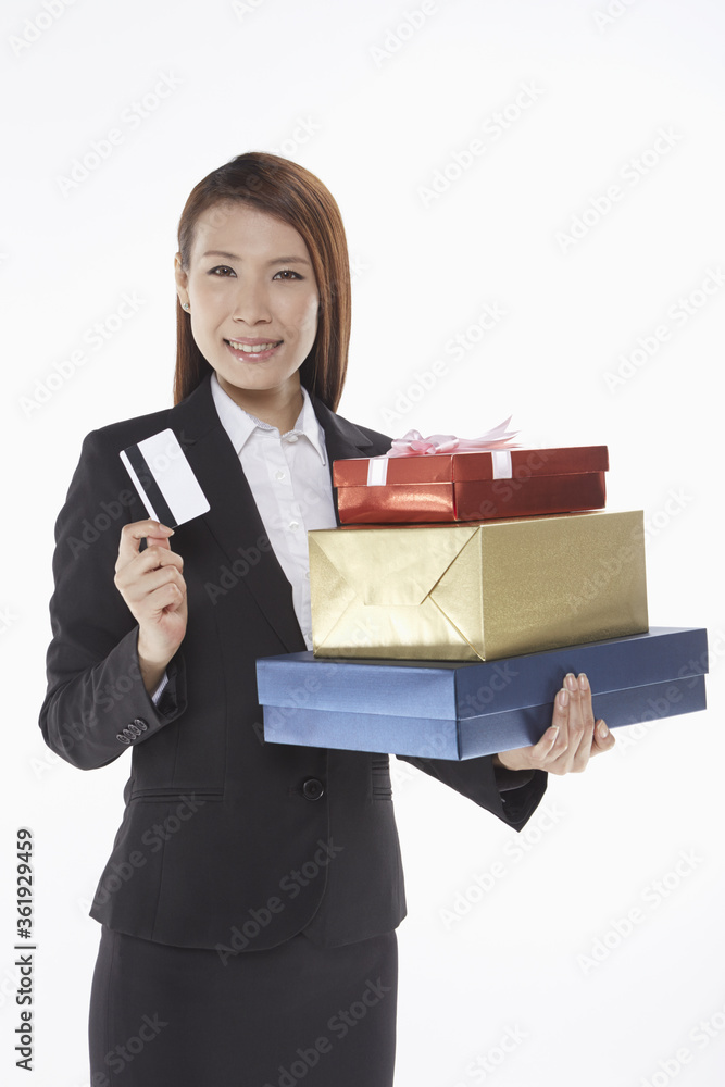 Businesswoman carrying a stack of gift boxes and holding a credit card Businesswoman carrying a stack of gift boxes and holding a credit card