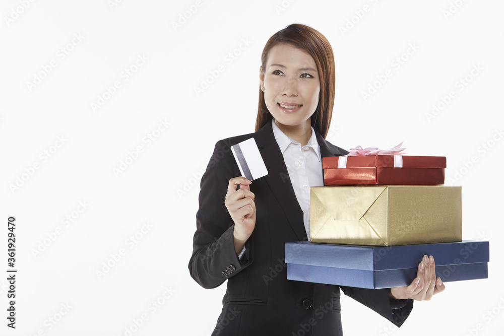 Businesswoman carrying a stack of gift boxes and holding a credit card Businesswoman carrying a stack of gift boxes and holding a credit card