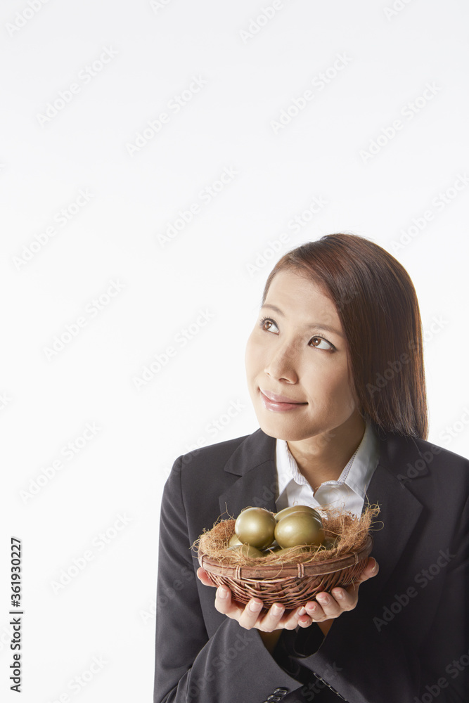 Businesswoman carrying a nest filled with gold eggs Businesswoman carrying a nest filled with gold eggs