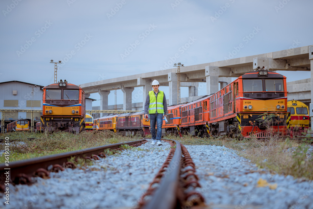 Fototapeta premium Portrait engineer under inspection and checking construction process railway switch and checking work on railroad station .Engineer wearing safety uniform and safety helmet in work.