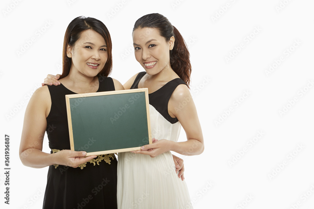 Two women holding up a blank blackboard Two women holding up a blank blackboard