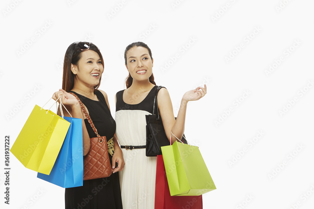 Cheerful women carrying paper bags and smiling Cheerful women carrying paper bags and smiling
