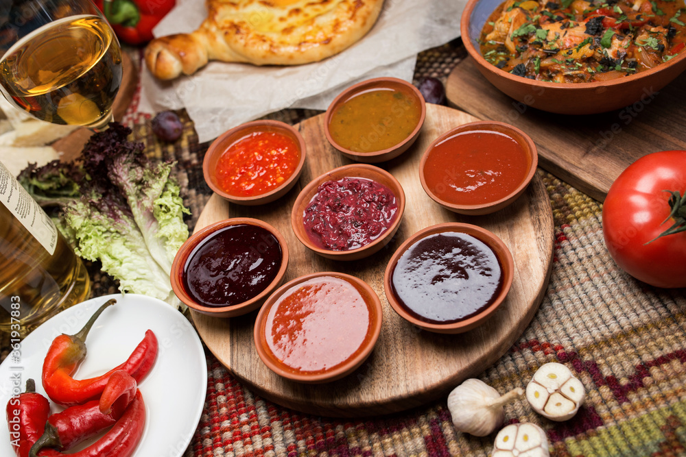 spicy sauces in round plates. cheese and vegetables around. close-up, top view. Georgian national cuisine