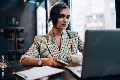 Caucasian female entrepreneur in smart casual wear watching online video during distance job, skilled woman reading received email newsletter with business news using 4g wireless connection on netbook