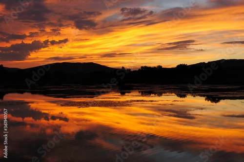 Lake  golden light at dusk. With reflection on the water surface. Beauty orange colored clouds . Dubnica  Slovakia.