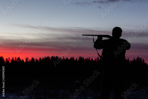 Silhouette of people with guns at sunset.