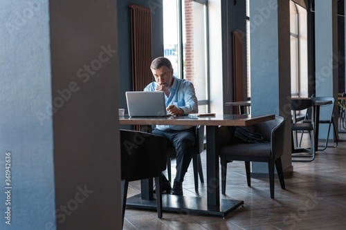 Mature businessman working on laptop. Handsome mature business leader sitting in a modern office