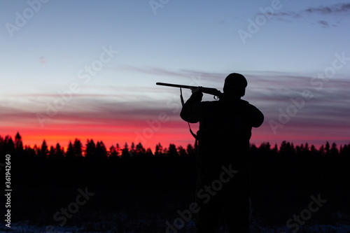 hunter aiming the hunting rifle during a hunt at sunrise