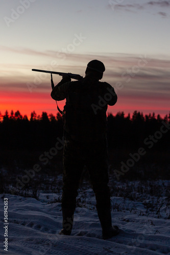 Silhouette of people with guns at sunset.
