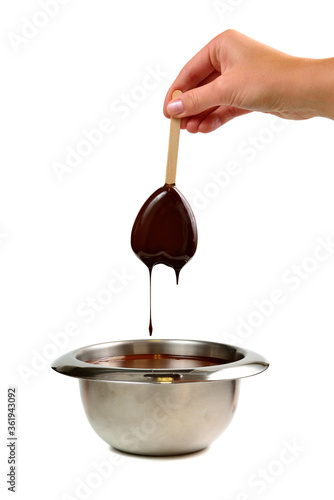 Hand dipping vanilla ice cream in heart shape on wooden stick in hot liquid dark chocolate