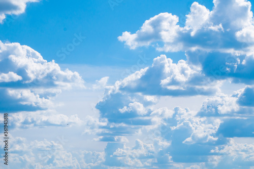 Many large fluffy clouds with a flat bottom against a large bright blue sky with a haze covered horizon