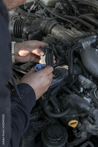 Car mechanic repairs car breakdowns, changes filter and changes spark plugs, ignition coil tip