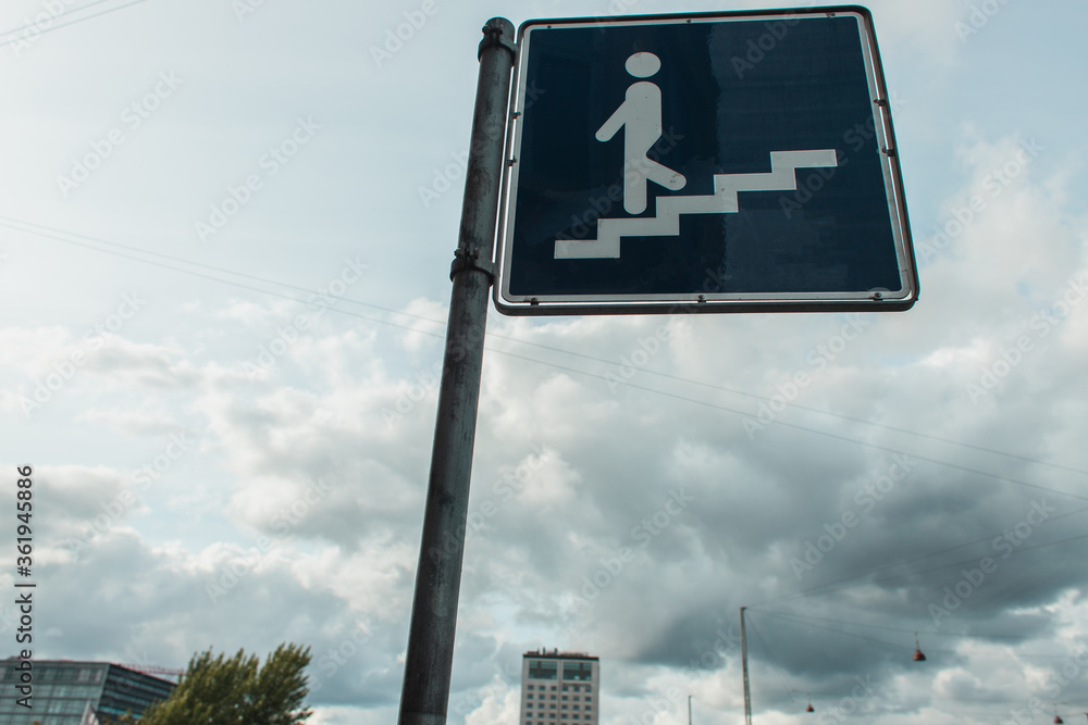 Low angle view of stairs sign on urban street with cloudy sky at background Low angle view of stairs sign on urban street with cloudy sky at background