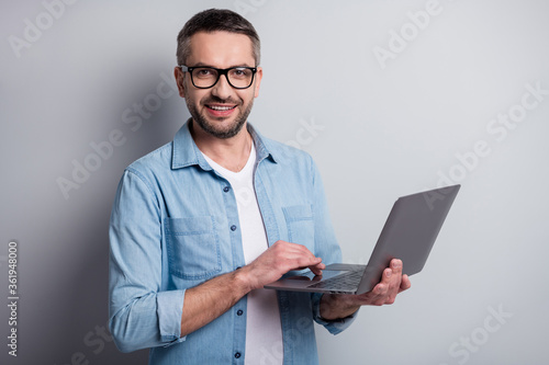 Close-up portrait of his he nice attractive content cheerful successful gray-haired guy digital company founder using laptop isolated over gray light pastel color background