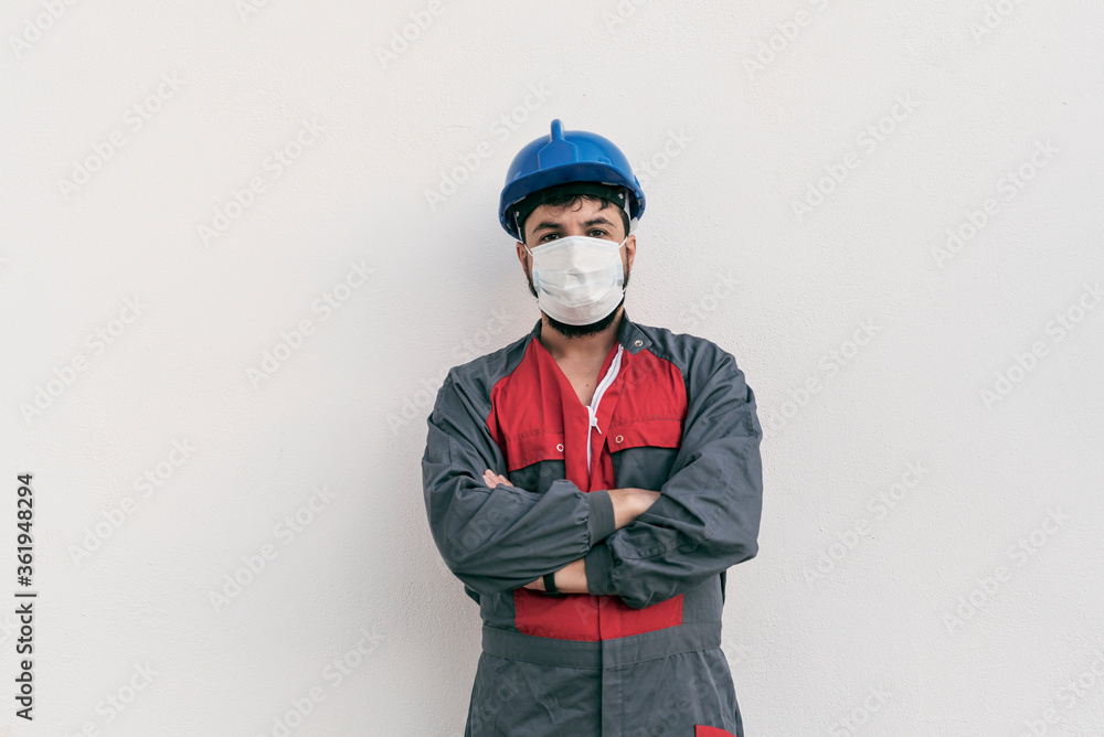 Construction worker portrait on white wall posing with face mask Covid -19 prevention