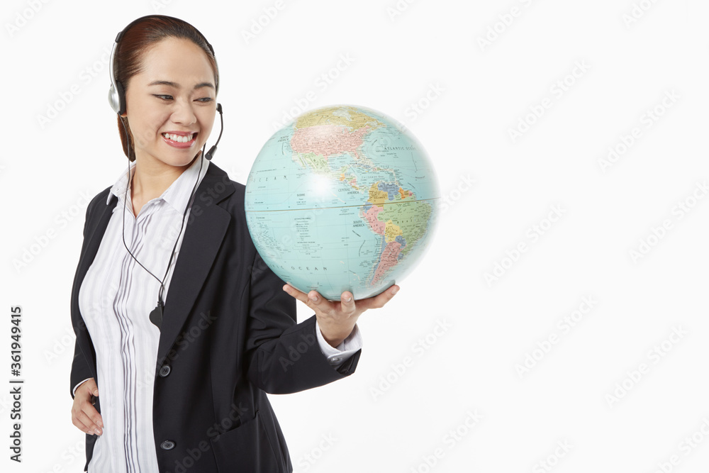 Businesswoman with headset holding a globe Businesswoman with headset holding a globe