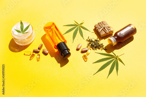 Natural cosmetics with hemp leaves. Cannabis oil and natural cream on a yellow background. Contrast shadows