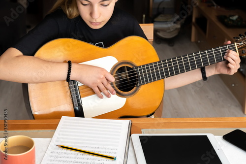 Little girl studying guitar lessons at home