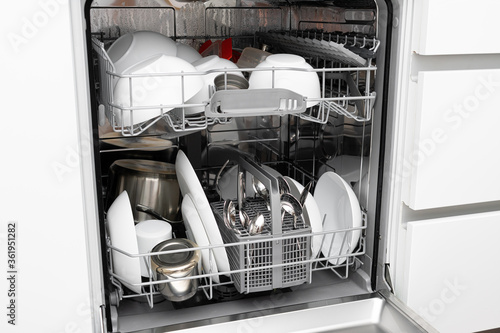 Loading a dishwasher. Dishwasher with clean dishes
