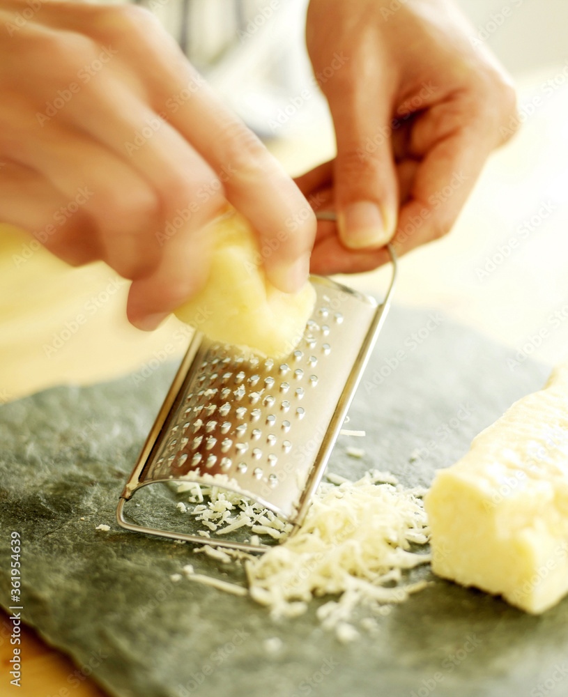 Chef grating Parmesan cheese onto a slate surface Stock Photo | Adobe Stock