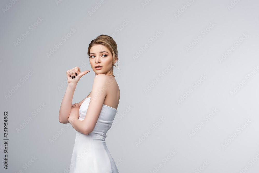 beautiful girl in white wedding dress pointing with thumb isolated on grey beautiful girl in white wedding dress pointing with thumb isolated on grey