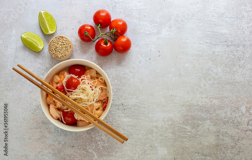 Dietary noodles shirataki konjak with shrimps and tomatoes in a bowl with chopsticks. Gluten-free and keto diet for weight loss. Copy space for text.