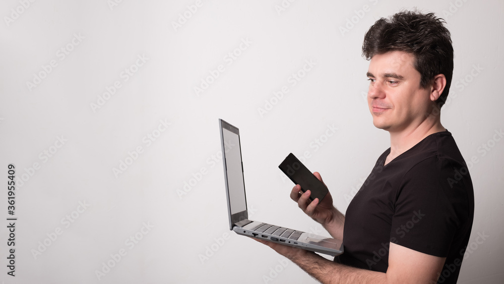 Man works on a laptop with a mobile phone. Happy man talking on a cell phone and laptop. Man works on a laptop with a mobile phone. Happy man talking on a cell phone and laptop.