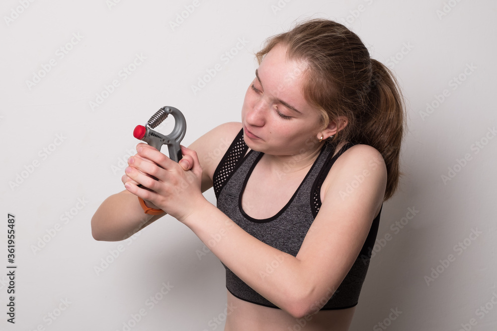 Funny girl in sportswear is training with an expander. Banner with blank space for text. Funny girl in sportswear is training with an expander. Banner with blank space for text.