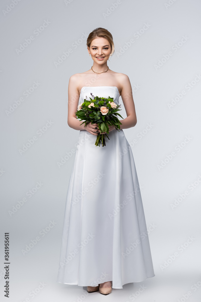 smiling girl in white wedding dress holding bouquet of flowers on grey smiling girl in white wedding dress holding bouquet of flowers on grey