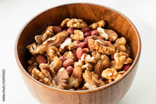 Mix of nuts in a wooden bowl on a white background