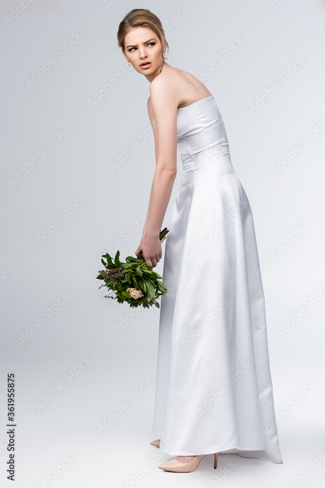 dissatisfied bride in elegant wedding dress holding bouquet of flowers on grey dissatisfied bride in elegant wedding dress holding bouquet of flowers on grey