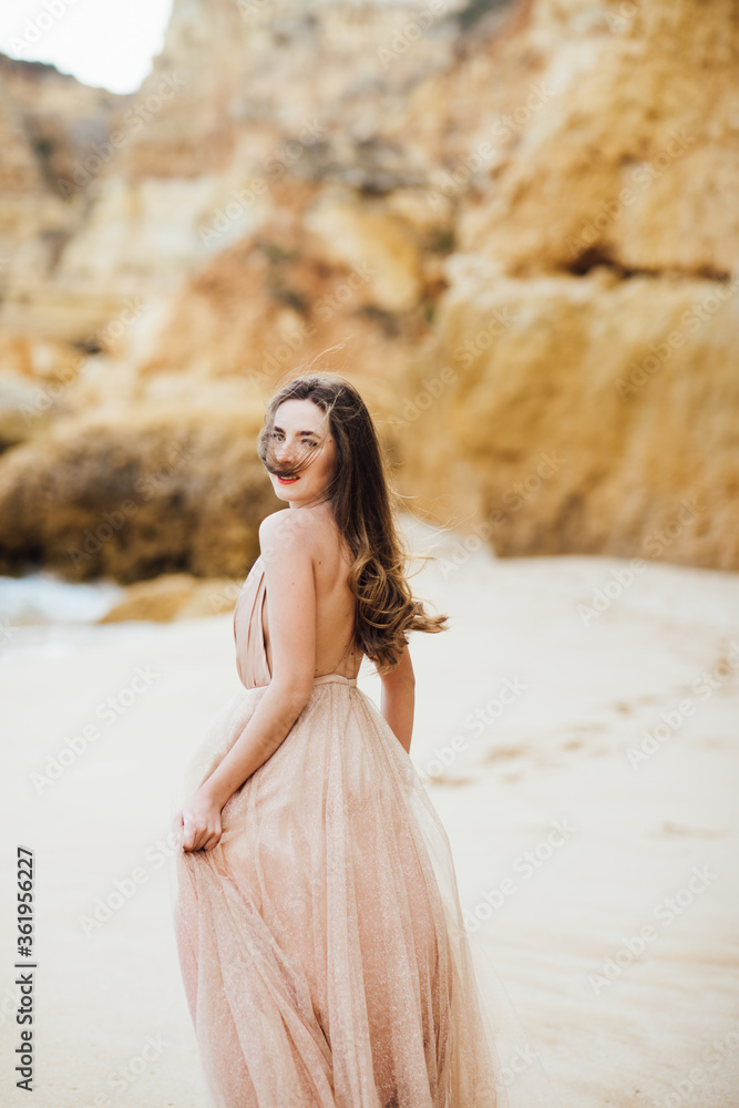 Back view of young woman in a long skirt walking on the ocean. Girl and the sea