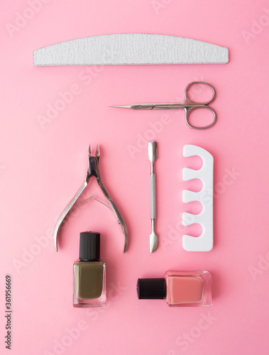 Fototapeta Naklejka Na Ścianę i Meble -  Manicure and pedicure nail care tools set on pink background knolling flat lay. Sponge separator, cuticle pusher, nail file, cuticle trimmer, purpose scissor, and colours nail polish in bottle