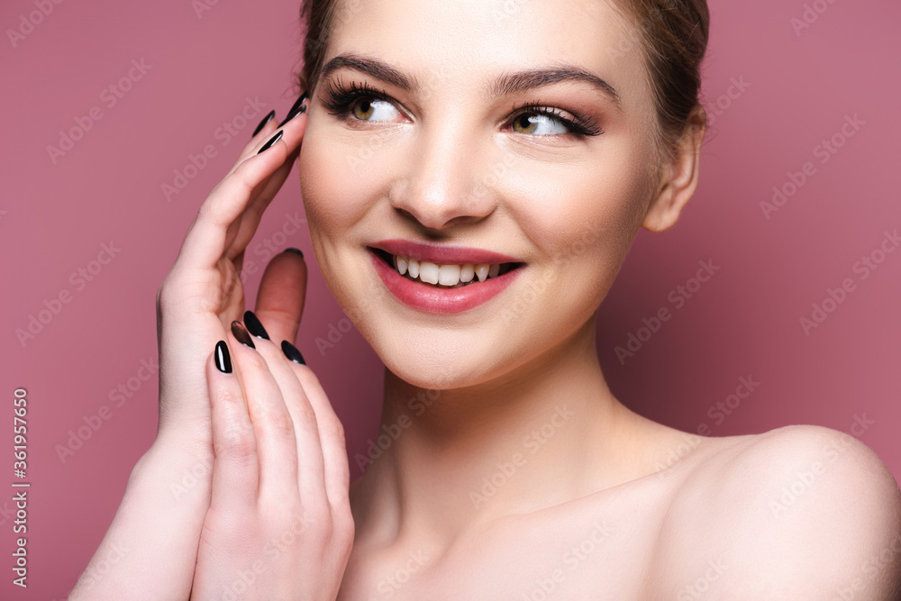 pretty girl with eye shadow and lipstick touching face and smiling on pink pretty girl with eye shadow and lipstick touching face and smiling on pink