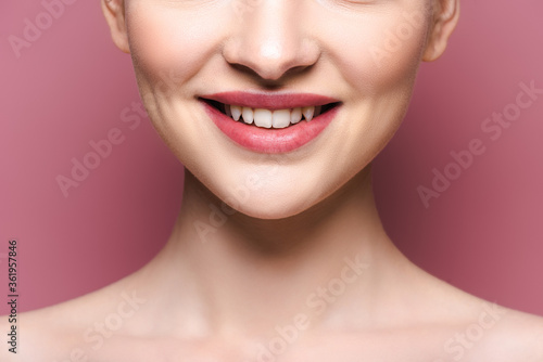 cropped view of happy young woman with lipstick on lips on pink