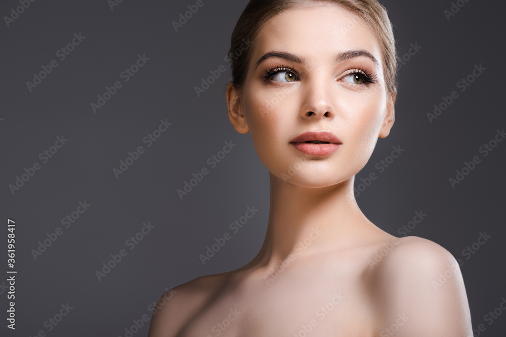 beautiful and naked woman with makeup looking away isolated on grey