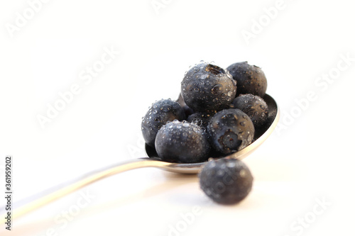 close-up of a spoon with blueberries on white Background