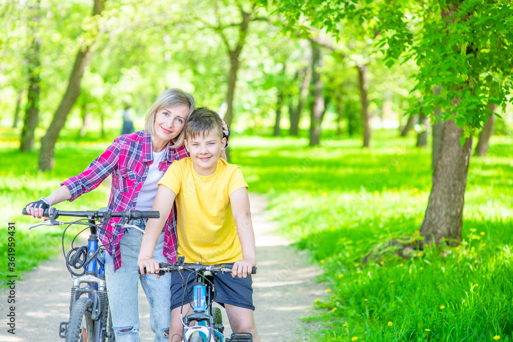 Portrait of a happy family holding bikes in a summer park. Smiling mother hugs her young son. Empty space for text Portrait of a happy family holding bikes in a summer park. Smiling mother hugs her young son. Empty space for text