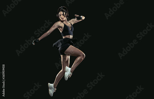 Beautiful young female athlete practicing on black studio background, full length portrait. Sportive fit brunette model in run, jump. Body building, healthy lifestyle, beauty and action concept. © master1305