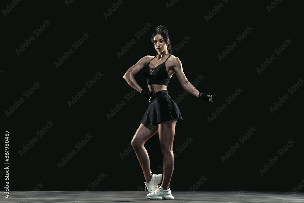 Beautiful young female athlete practicing on black studio background, full length portrait. Sportive fit brunette model posing confident. Body building, healthy lifestyle, beauty and action concept. Beautiful young female athlete practicing on black studio background, full length portrait. Sportive fit brunette model posing confident. Body building, healthy lifestyle, beauty and action concept.
