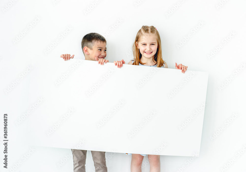Happy boy and girl children holding big blank poster Happy boy and girl children holding big blank poster