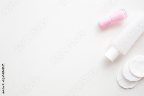 Glass bottle of pink nail polish. Plastic bottle of lacquer remover. White cotton pads. Manicure, pedicure beauty salon concept. Empty place for text or logo on light gray background. Top down view.